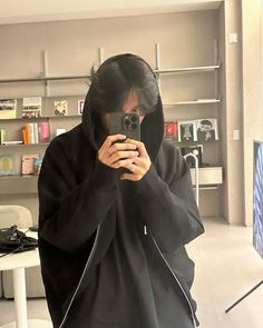 a woman taking a selfie in front of a mirror wearing a black hoodie