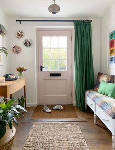 a living room with green curtains and rugs on the floor next to a white door