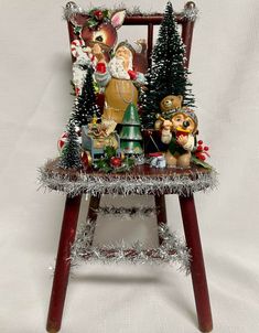 a wooden chair decorated with christmas decorations and figurines on top of tinsel