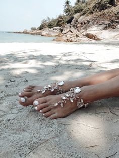 a woman's feet covered in shells on the beach