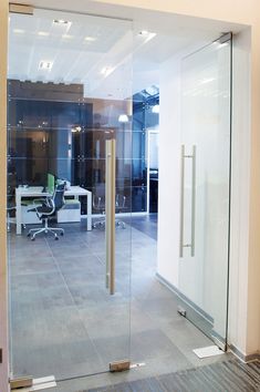 an office with glass walls and desks in the center, along with a door leading to another room