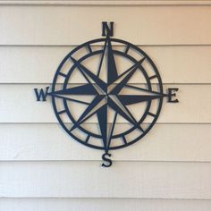 a metal compass is mounted to the side of a white house with black lettering on it