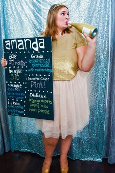 a woman in a dress holding a sign with words written on it and drinking from a bottle