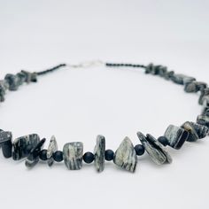 Discover the epitome of masculine elegance with our handmade Men's Gemstone Necklace. Meticulously crafted using a blend of Black Silk Stone chip beads and Matte Black Onyx gemstones, this necklace exudes a sense of strength and sophistication. Elevate your style with the dark allure of these genuine gemstones, carefully chosen to create a piece that complements any look. The necklace is 18 inches long with the option to add a chain extender. Features a pewter fish hook clasp for easy of use. Adjustable Obsidian Necklace With Natural Stones, Obsidian Necklace With Natural Stones, Adjustable Onyx Gemstone Beads Crystal Necklace, Adjustable Onyx Crystal Necklace With Gemstone Beads, Masculine Elegance, Chip Necklace, Rain Design, Latest Jewellery Trends, Stone Chips