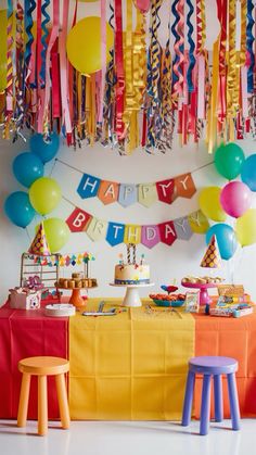 a birthday party with balloons and streamers hanging from the ceiling, colorful table cloths