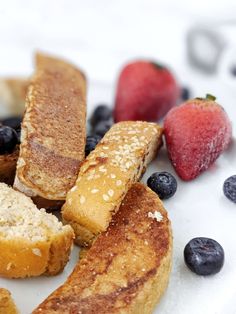 some blueberries, strawberries and bread on a white plate with powdered sugar