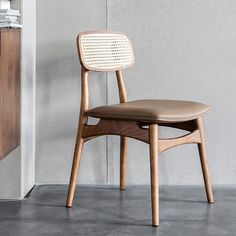 a wooden chair sitting next to a white wall