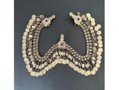 This antique silver bridal headpiece/necklace is a beautiful piece of Ottoman art, handcrafted with intricate details that make it unique. The necklace has a striking silver color that gives it a vintage and antique feel. It was produced before 1920 and is a testament to the quality workmanship of that period. The jewelry department classifies it as costume jewelry, but it is made of low-carat silver and is a valuable piece for collectors. It can be worn as a necklace, headpiece or traditional p White Bohemian Necklace With Tilla Detail, White Bohemian Jewelry With Tilla, Bohemian White Jewelry With Tilla, Bohemian White Tilla Jewelry, White Bohemian Tilla Necklace, Traditional Silver Necklaces For Ceremonies, Heavy Ornate Silver Bridal Necklace, Ornate Heavy Silver Bridal Necklace, Ornate Motif Jewelry For Weddings