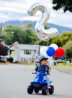 a little boy riding a toy motorcycle with balloons attached to it