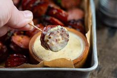 a person dipping something into a bowl with some kind of food in it on a stick