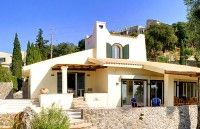 the house is white and has green shutters on it's sides, with trees in the background