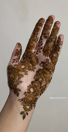 a hand with henna on it and some flowers in the middle of its palm