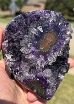 a person is holding a large piece of ametholite in their hand outside