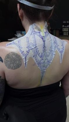 the back of a woman's shoulder with tattoos on it