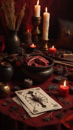 a table topped with candles and other items on top of a red cloth covered table