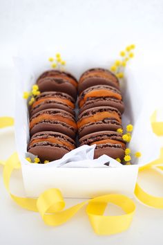 a box filled with chocolate covered cookies on top of a white table next to yellow ribbons