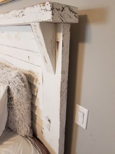 a white headboard made out of wood with pillows and blankets on the bottom shelf