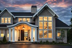 a large gray house with white trim and two story windows on the front door at dusk