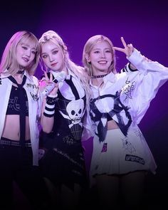 three girls posing for the camera in front of a purple background with their hands up