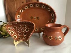 three pieces of pottery sitting on top of a white countertop next to a potted plant