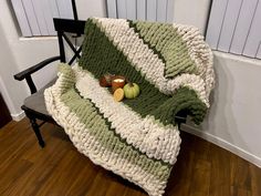 a green and white blanket sitting on top of a chair next to a wooden floor