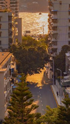 an aerial view of the ocean and city with buildings in the foreground at sunset