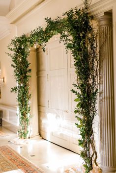 an archway decorated with greenery in the middle of a room next to a doorway