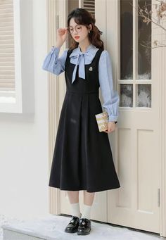 Faux two-piece layered dress with a stripe blouse with two buttons and a tie-up neckline, and a solid colored pinafore dress with a varsity embroidered badge, elastic waist and waist ties. S: 35.5" chest, 27" waist, 42" lengthM: 37" chest, 28.5" waist, 42" lengthL: 38.5" chest, 30" waist, 42" length Flannel Pinafore Dress, Spring Sleeveless School Uniform Dresses, Preppy Dresses For Work In Fall, Preppy Dresses For Fall Workwear, Preppy Spring Workwear Dresses, Preppy Fall Workwear Dresses, Casual Fall Pinafore Dress For Workwear, Long Sleeve Suspender Dress For Spring, Spring Workwear Fake Two-piece Dresses