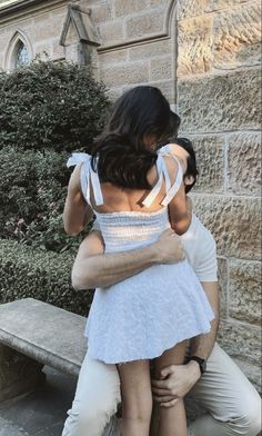 a man and woman hug each other in front of a bench