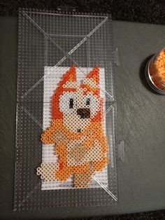 an orange and white cross - stitch animal sitting on top of a piece of plastic