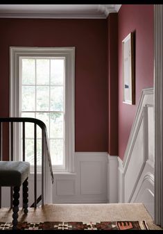 an empty room with red walls and white trimmings, along with a rug on the floor