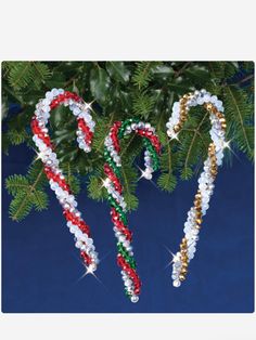 two candy canes are hanging from a christmas tree with stars on it and one is made out of plastic beads