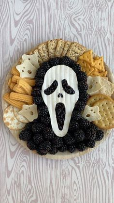 a plate with crackers and blackberries in the shape of a scream face