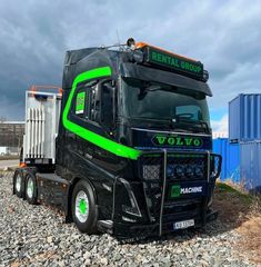 a black and green semi truck parked on gravel