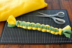 a yellow and green caterpillar sitting on top of a cutting board next to scissors