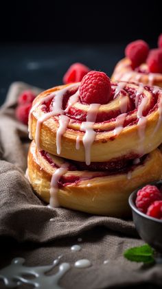 raspberry cinnamon rolls with icing drizzled over them and fresh raspberries