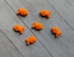 six orange fish shaped cookies sitting on top of a wooden table