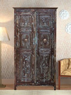 an old wooden armoire sitting next to a lamp in a room with wallpaper