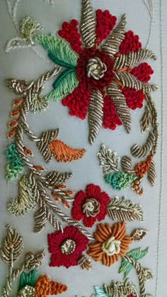 a close up of a piece of cloth with flowers and leaves embroidered on the side