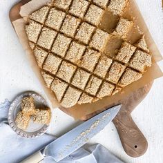 a cutting board topped with cut up squares of food next to a knife and bowl