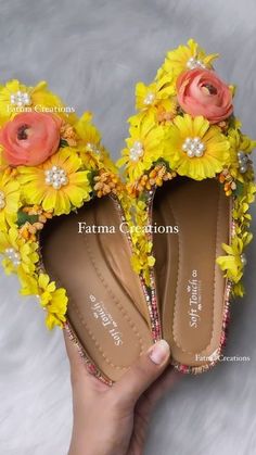 a pair of yellow shoes with flowers on the soles are being held by a woman's hand