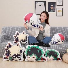 a woman sitting on a couch holding up some pillows with anime character faces printed on them