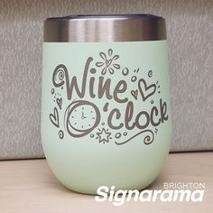 a wine glass with the words wine oclock painted on it, sitting on a table