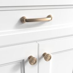 a close up view of the handles on a white cabinet with brass pulls and knobs