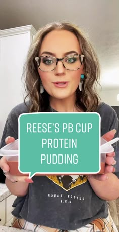 a woman holding up a sign that says reese's pb cup protein pudding