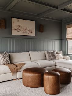 a living room with couches and ottomans in front of a large painting on the wall