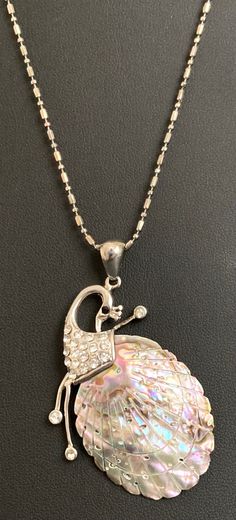 a necklace with a shell on it and a silver ball hanging from the back of it