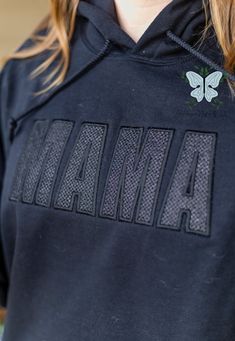 Elevate your mom style with our Mama Black Embroidered Glitter Vinyl Crewneck Sweatshirt! Made with high-quality materials, this cozy black sweatshirt is stitch filled embroidered with the word "Mama" in a bold and chic font. The shimmering black glitter vinyl adds a touch of glamour, while the crewneck design provides comfort and style. Perfect for any mama looking to show off her love and style at the same time! THIS IS A PHYSICAL PRODUCT. CREWNECK IS UNISEX. CREWNECK IS EMBROIDERED. CREWNECK Black Hoodie With Embroidered Graphics For Fall, Black Top With Custom Embroidery For Winter, Black Tops With Custom Embroidery For Winter, Embroidered Black Hoodie For Fall, Black Cotton Sweatshirt With Letter Embroidery, Black Embroidered Hoodie For Fall, Black Casual Sweatshirt With Letter Embroidery, Black Sweatshirt With Custom Embroidery For Fall, Black Crew Neck Hoodie With Letter Embroidery