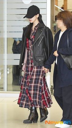 a woman in a plaid dress and black hat is holding the hand of another woman