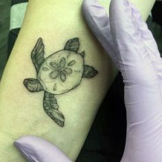 a woman's arm with an apple and turtle tattoo on the left side of her arm